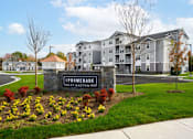 Thumbnail 1 of 35 - Promenade at Easton is a residential complex with a well-maintained lawn and flower beds at The Promenade at Easton Apartments, Easton