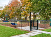 Thumbnail 25 of 35 - A playground with a black fence and a green slide at The Promenade at Easton Apartments, Easton, MD 21601