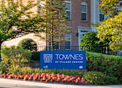 Thumbnail 26 of 50 - a building with a blue sign in front of it at Townes at Village Center Apartments, Reisterstown, Maryland