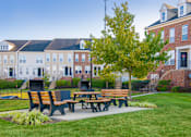 Thumbnail 16 of 50 - a patio with benches and a table in front of a building at Townes at Village Center Apartments, Maryland, 21136