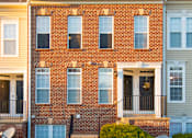 Thumbnail 38 of 50 - the front of a brick apartment building with stairs and a lawn at Townes at Village Center Apartments, Reisterstown, 21136