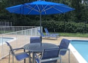 Thumbnail 13 of 14 - A blue umbrella is above a round table with four chairs.