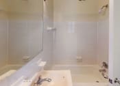 Thumbnail 8 of 14 - A white bathroom with a tub and shower.