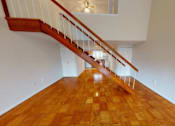 Thumbnail 10 of 14 - A wooden staircase with a white railing leads up to a second floor.