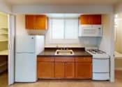 Thumbnail 7 of 14 - A kitchen with white appliances and wooden cabinets.