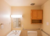 Thumbnail 10 of 14 - A bathroom with a toilet, sink, and mirror.