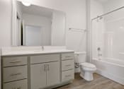 Thumbnail 6 of 19 - A white bathroom with a sink, toilet, and bathtub.