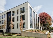 Thumbnail 7 of 19 - A modern building with a grey facade and black windows.