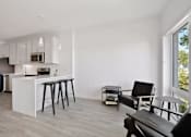 Thumbnail 10 of 19 - A kitchen with white cabinets and a white island with bar stools.