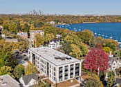 Thumbnail 19 of 19 - A large white building with a grey roof is surrounded by trees in autumn colors.