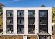 Thumbnail 1 of 19 - A modern building with a white facade and black windows.