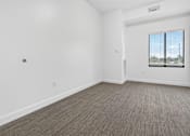 Thumbnail 51 of 52 - A room with a carpeted floor and a window with blinds.