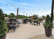 Thumbnail 25 of 52 - A patio with tables and chairs and string lights.