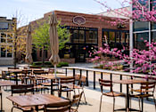 Thumbnail 60 of 64 - A restaurant with tables and chairs outside with a blue sky in the background.