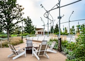 Thumbnail 31 of 34 - A patio with chairs and a table is surrounded by trees.