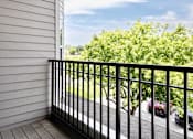 Thumbnail 61 of 61 - A balcony with a black railing overlooks a street with cars and greenery.