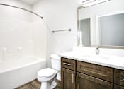 Thumbnail 59 of 61 - A white toilet sits in a bathroom with a white tub and a white sink.