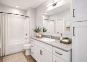 Thumbnail 6 of 40 - A white bathroom with a toilet, sink, and shower.