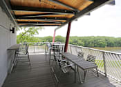 Thumbnail 20 of 50 - A wooden deck with metal chairs and tables overlooking a body of water.