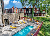 Thumbnail 1 of 50 - A pool surrounded by chairs and tables in a sunny backyard.