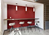Thumbnail 34 of 50 - A red wall with a table and three stools in front of it.