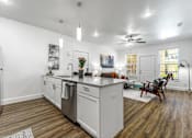 Thumbnail 9 of 28 - A modern kitchen with white cabinets and a wooden floor.