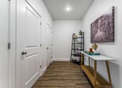 Thumbnail 15 of 28 - A hallway with a white door and a white table with a plant on it.