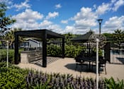 Thumbnail 31 of 35 - A black metal structure is in the middle of a garden with a table and chairs.