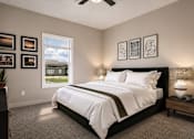 Thumbnail 6 of 35 - A bedroom with a large bed, a ceiling fan, and pictures on the wall.