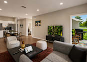 Thumbnail 16 of 35 - A modern living room with a grey couch, a black coffee table, and a red rug.