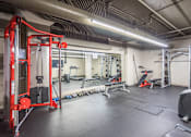 Thumbnail 34 of 35 - A gym with a red weight machine and various other equipment.