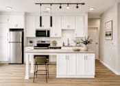 Thumbnail 4 of 40 - A kitchen with white cabinets and a wooden floor.