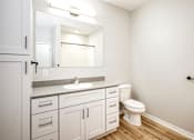 Thumbnail 22 of 34 - A white bathroom with a sink, toilet, and cabinets.