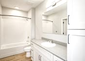 Thumbnail 21 of 34 - A white bathroom with a toilet, sink, and mirror.