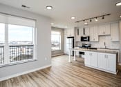 Thumbnail 13 of 34 - A kitchen with white cabinets and a large window overlooking a parking lot.