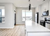 Thumbnail 9 of 34 - A modern kitchen with white cabinets and black appliances.