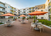 Thumbnail 3 of 19 - a large patio with tables and umbrellas in an apartment complex