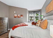 Thumbnail 20 of 43 - A bedroom with a white bed and a red throw on it.