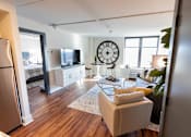 Thumbnail 18 of 22 - A living room with a couch, a chair, a television, and a clock on the wall at Cityplace Apartment Homes Apartments, Pennsylvania