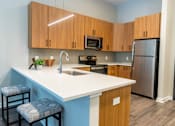 Thumbnail 8 of 26 - A kitchen with a white countertop and wooden cabinets at The Hive Apartments, Allentown, Pennsylvania