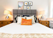 Thumbnail 14 of 26 - A bed with a white comforter and a grey headboard with a pillow on it at The Hive Apartments, Allentown 18101