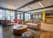 Thumbnail 21 of 26 - A modern living room with a wooden coffee table and a grey ottoman at The Hive Apartments, Allentown