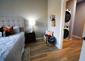 Thumbnail 10 of 15 - A bedroom with a bed, nightstand, and basket on the floor.