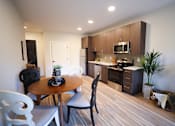 Thumbnail 5 of 15 - A modern kitchen with a dining table and chairs.