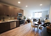 Thumbnail 2 of 15 - A modern kitchen with wooden floors and furniture.