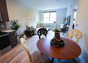 Thumbnail 6 of 15 - A living room with a brown table and chairs.