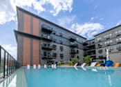 Thumbnail 19 of 22 - A swimming pool in front of a modern building with a clear blue sky above.