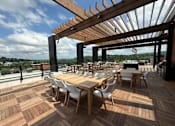 Thumbnail 22 of 22 - A wooden deck with tables and chairs and a pergola.