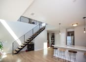 Thumbnail 11 of 16 - a living room with a staircase and a kitchen with a bar