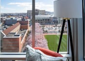 Thumbnail 3 of 16 - a view of the city from a hotel room with a chair and a lamp